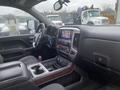 Interior of a 2015 GMC Sierra 1500 featuring a steering wheel dashboard and center console with a touchscreen display and various control buttons