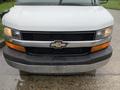 Front view of a white 2015 Chevrolet Express van featuring a black grille with a prominent Chevrolet emblem and an orange accent on the bumper