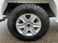 A close-up view of a silver alloy wheel with five spokes and a large all-terrain tire labeled with the brand name and model on its sidewall