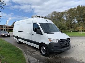 A white 2019 Mercedes-Benz Sprinter van with a high roof and refrigeration unit on top parked on a driveway