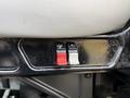 Two buttons on a dashboard panel of a 2011 International WorkStar one is red and the other is white both have symbols indicating their functions