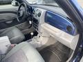 Interior of a 2007 Chrysler PT Cruiser featuring a light gray dashboard with blue accents a radio control panel and seats with patterned fabric
