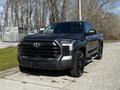 A 2023 Toyota Tundra in black featuring a bold front grille and distinctive design elements with large wheels and a sturdy stance