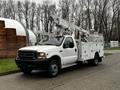 A white 2004 Ford F-450 SD bucket truck with an elevated lift and utility compartments on the side