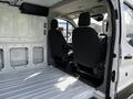 Interior view of a 2018 Ford Transit showing two front seats and an empty cargo space with a clean white floor