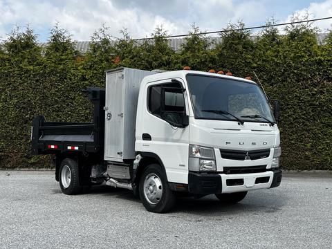 A 2015 Mitsubishi Fuso FE with a cab-over design features a silver cargo box and a black flatbed in the rear with five orange lights on the roof