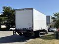 A white 2015 Freightliner M2 106 truck with a boxy cargo area parked with its back facing the viewer