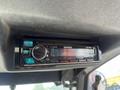 A Kenwood CD player mounted inside the cabin of a Toro Groundmaster 5910 featuring a digital display with FM radio tuning and various control buttons