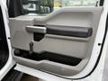 Close-up of the driver's side door panel of a 2017 Ford F-550 featuring a gray interior with a handle and manual window controls