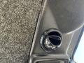 A close-up of a black air vent in a vehicle dashboard with a textured surface visible around it