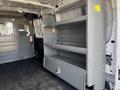 A 2016 Ford Transit van interior with metal shelving units mounted on one side and a visible fire extinguisher attached to the wall