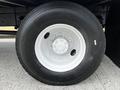 Close-up of a black tire with a silver wheel rim featuring multiple bolts and the text Strong Grip on the sidewall