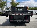 A black 2016 Ford F-550 truck with a flatbed and metal grille at the rear displaying a logo and lights