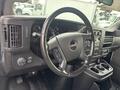Interior view of a 2022 GMC Savana showing the steering wheel dashboard and center console with controls and cup holders