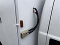 A close-up of a connector and wiring attached to a white surface on a 2000 Ford F-450 with water droplets on it