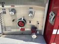 A metallic control panel featuring valves and hoses from a 1994 Volvo FE 42 fire truck with a prominent red and black emblem at the center