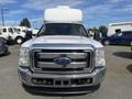 A white 2014 Ford F-350 Super Duty with a large box on the roof parked in a lot facing the camera with a chrome front grille and visible Ford emblem