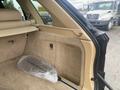 A 2009 BMW X5 with an open rear cargo area showing beige interior upholstery and storage compartment