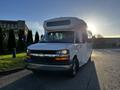 A white 2017 Chevrolet Express with a high roof and large front windshield parked on a street