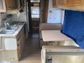 The image shows the interior of a 1987 Chevrolet Fleetwood Pace Arrow with a kitchen area featuring a sink and stove a dining table and seating area