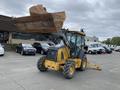 A 2012 John Deere 310SJ backhoe loader with a large front bucket and rear excavator arm positioned on a concrete surface