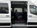 Side view of a 2021 Ford Transit van with the sliding door open revealing several seats inside
