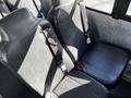 Two black, vinyl-covered seats with seatbelts inside a school bus vehicle