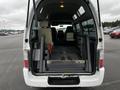 A white 2002 Nissan Van with its rear door open revealing an empty cargo area and folding wheelchair ramp