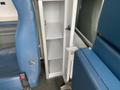 A 2014 Chevrolet Express featuring a compact storage cabinet with multiple shelves located between two blue seats