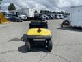 A 1999 Ez-go Industrial vehicle with a yellow body and black seat parked on an asphalt surface