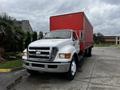 A white 2008 Ford F-750 with a red cargo box parked on a paved surface, featuring a large front grille and multiple axles