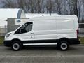 A white 2020 Ford Transit van with a high roof and sliding side door parked on a street, viewed from the side