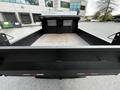 A 2015 Mitsubishi Fuso FE truck featuring an open flatbed with a textured metal floor and a black exterior