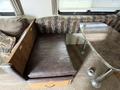 A brown leather cushioned bench seat with a wooden frame and a table with a marble-like surface in an indoor setting