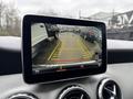 A view from the rear backup camera display of a 2016 Mercedes-Benz GLA-250 showing parking guidelines and nearby vehicles