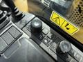 Control panel of a 2022 Caterpillar 306 featuring multiple switches and dials with a textured surface and warning labels visible