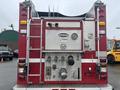 A red 2006 E-One Typhoon fire truck with silver equipment panels hoses and ladder attachments visible on the rear side