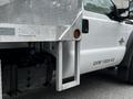 A 2011 Ford F-550 featuring a white exterior with a metal flatbed and visible vehicle identification details on the side of the truck