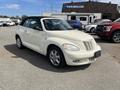 A 2005 Chrysler PT Cruiser in a cream color with a convertible top parked in a lot