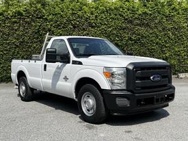 A 2012 Ford F-250 truck in white with a black grille and front bumper featuring a single cab design and a flatbed in the back