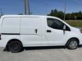 A white 2019 Nissan NV200 van with a side door open and a spare tire visible on the rear passenger side