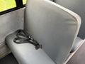 A gray cushioned bus seat with a black seatbelt attached