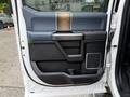 A 2018 Ford F-150 door interior featuring a dark trim with wood accents and storage compartments