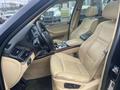 Interior of a 2009 BMW X5 featuring cream leather seats a wood trim dashboard and a gear shift in the center console