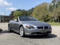 A silver 2004 BMW 6-Series convertible with a sleek design and large alloy wheels parked on a road