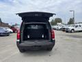 A 2016 Chevrolet Tahoe with the rear hatch open showing a spacious cargo area with a metal divider and no visible items inside