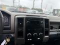 The dashboard of a 2011 Dodge Ram 5500 featuring dials buttons and a media display with raindrops on the windshield
