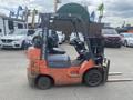 A 2010 Toyota 7FGGU25 forklift with an orange body and black accents featuring two forks at the front and a steering wheel on the left side