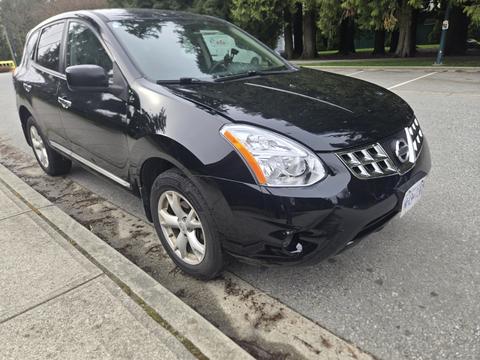 A black 2011 Nissan Rogue parked on the side of a street with silver alloy wheels and a sleek design