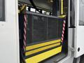 A lowered wheelchair ramp with a metal mesh surface and yellow and red safety markings on a 2018 Chevrolet Express van